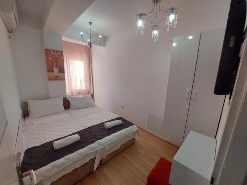 a bedroom with a bed with white sheets and a chandelier at Petreski Apartments 1 in Ohrid