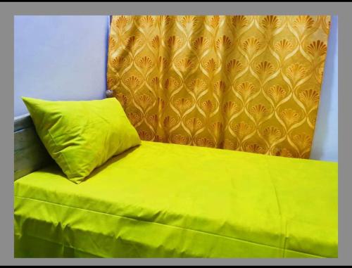 a yellow pillow sitting on top of a bed at GREEN GRASS HOUSE in Colombo