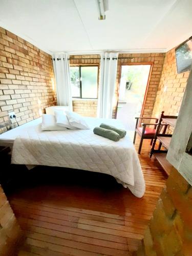 Van StadensriviermondにあるWhispering Wavesのレンガの壁に大きなベッドが備わるベッドルーム1室が備わります。