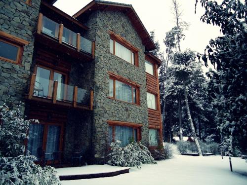 a building with snow on the ground in front of it at Hosteria Patagon in Villa La Angostura