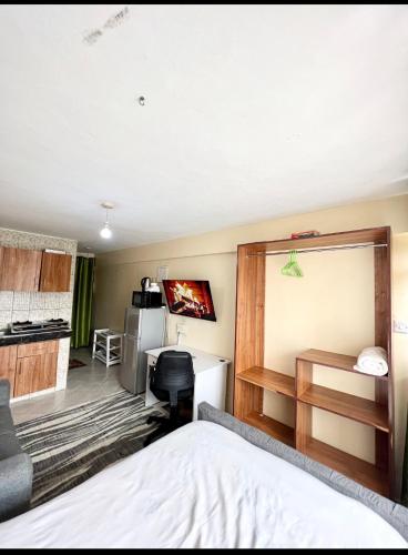 a bedroom with a bed and a desk and a kitchen at SABU HOMEs in Nairobi