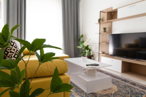 een woonkamer met een gele bank en een witte tafel bij Cozy Central Apartment in Larisa