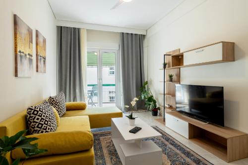 sala de estar con sofá amarillo y TV de pantalla plana en Cozy Central Apartment, en Larisa