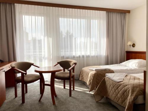 Habitación de hotel con cama, mesa y sillas en Senator, en Katowice
