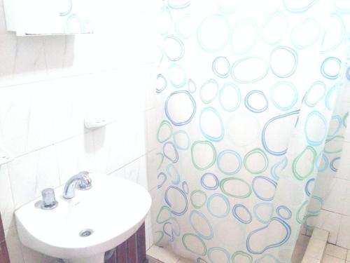 a bathroom with a sink and a shower curtain at Cabañas Viña Aliwen in Vistalba