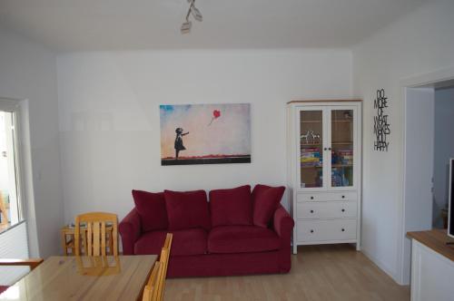 ein Wohnzimmer mit einem roten Sofa und einem Tisch in der Unterkunft Apartment Moni in Lutzmannsburg, 1 km von der Sonnentherme entfernt - Apartment mit 3 Schlafzimmern in Lutzmannsburg