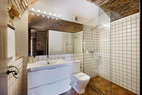 a bathroom with a toilet and a sink and a mirror at Masia Torre Lloreta S.XIII in Calonge
