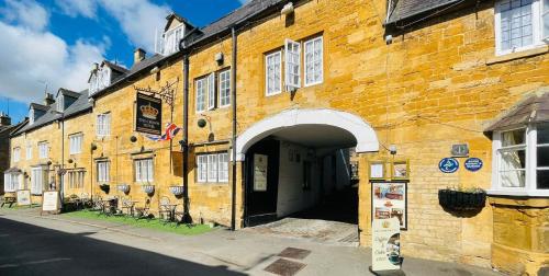 a large brick building with an archway on a street at Crown Hotel Cotswold in Blockley