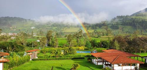 un arcobaleno sopra una casa con giardino e piscina di Eco Avocado Lodge a San José de Minas