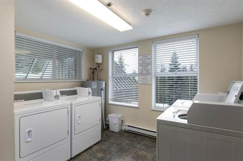 a kitchen with white appliances and two windows at Bright 2 bedroom and loft suite in the Wildwood Lodge in Whistler