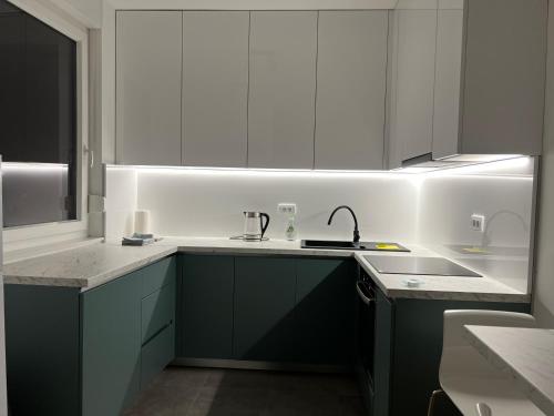 a kitchen with white and green cabinets and a sink at Apartman EMA in Banja Luka