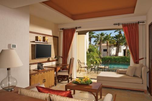 a living room with a couch and a table and a television at Secrets Puerto Los Cabos Golf & Spa18+ in San José del Cabo