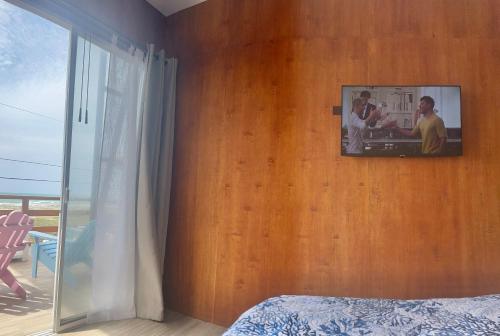a bedroom with a tv on a wooden wall at Casa Caballito de mar-Seahorse House in Bahía de Caráquez
