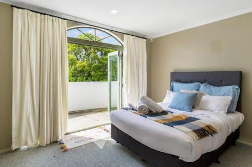 1 dormitorio con cama grande y ventana grande en Nature Serenity Getaway with pool - deck - gardens en Auckland