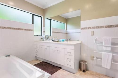 a white bathroom with a tub and a sink at Nature Serenity Getaway with pool - deck - gardens in Auckland