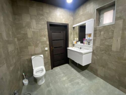 ein Badezimmer mit einem WC, einem Waschbecken und einem Spiegel in der Unterkunft Дом in Cǝnubi