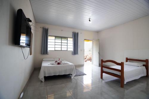 a room with two beds and a table and a chair at Pousada Mota in Bonito