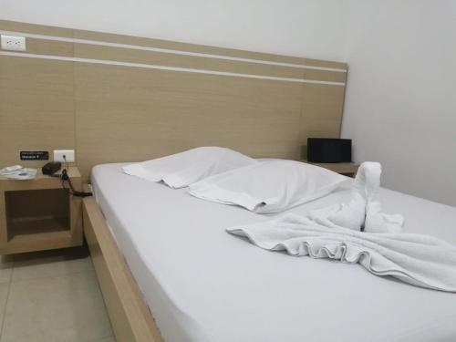 MOTEL CUPIDO (PALMIRA) في بالميرا: سرير عليه شراشف بيضاء ومناشف