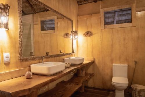 a bathroom with two sinks and a toilet at Mansur Hotelaria de Charme in Luis Correia