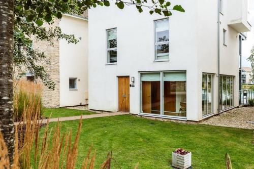 a white house with a green yard at Skylark Lodge HM24 HOT TUB Lakeside Spa in Somerford Keynes