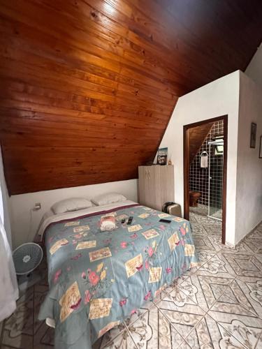 ein Schlafzimmer mit einem Bett und einer Holzdecke in der Unterkunft Chalé 3 Descanso nas Nascentes in Salesópolis