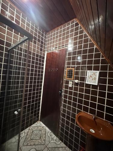 ein Badezimmer mit einem Waschbecken und einer braunen Tür in der Unterkunft Chalé 3 Descanso nas Nascentes in Salesópolis