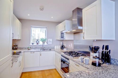 a kitchen with white cabinets and a stove top oven at Pennyroyal Lodge HM31 Lakeside Spa Property in Somerford Keynes