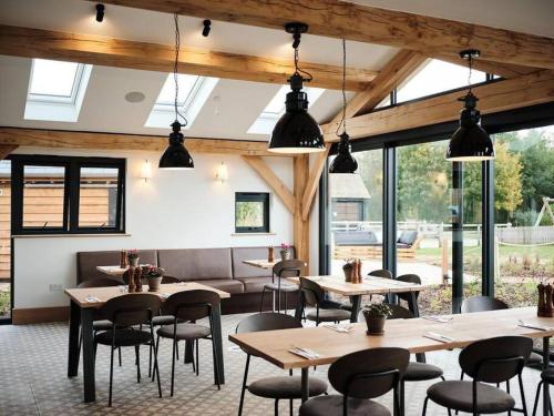 a restaurant with tables and chairs and windows at Pennyroyal Lodge HM31 Lakeside Spa Property in Somerford Keynes