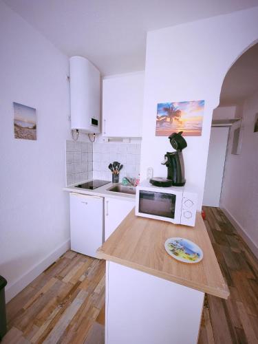 a kitchen with white cabinets and a counter with a plate on it at Studio vacances proche de la mer in Le Grau-du-Roi
