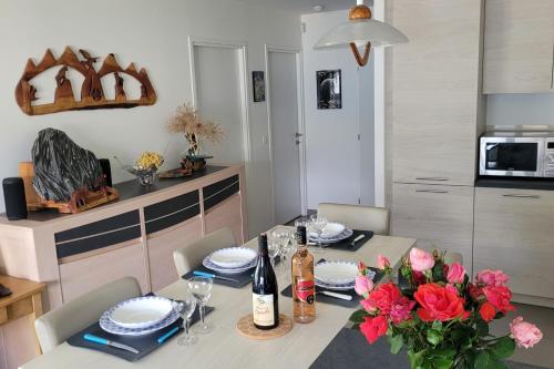 - une table à manger avec des fleurs et des bouteilles de vin dans l'établissement Le Tableau du Lac 507 - 2 bedrooms apartment with lake view terrace, à Annecy