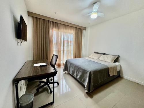 1 dormitorio con cama, escritorio y ventana en Suite privativa na Barra da Tijuca, RJ - Neolink Stay, en Río de Janeiro