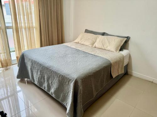 uma cama com um cobertor cinzento e almofadas num quarto em Suite privativa na Barra da Tijuca, RJ - Neolink Stay no Rio de Janeiro