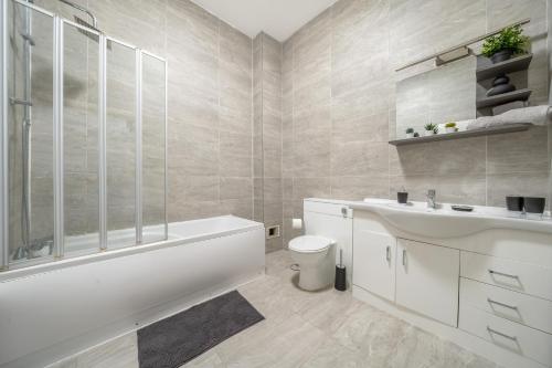 a bathroom with a tub and a toilet and a sink at Spacious City Centre Apartment - Sleeps 8 in Liverpool