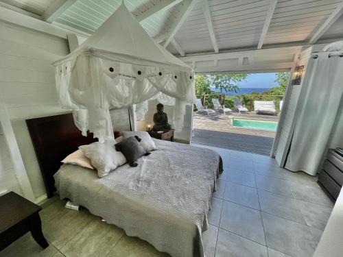 a bedroom with a canopy bed and a pool at Villa Orsalina Pointe Batterie in Deshaies