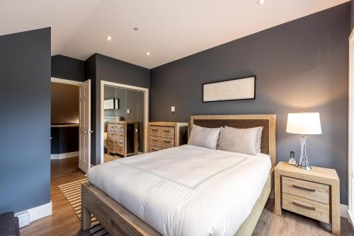 een slaapkamer met een groot wit bed en een zwarte muur bij Renovated Lynx Property - Spacious 4 bedroom with private balcony and hot tub! in Whistler