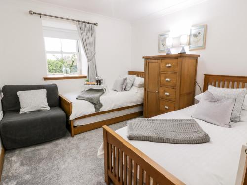 a bedroom with two beds and a chair at The Bungalow in Maybole