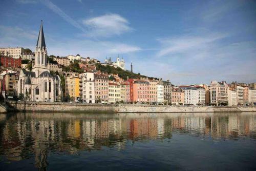 um grupo de edifícios numa colina ao lado de uma massa de água em Le Rhône à vos pieds, Bellecour à quelques pas em Lyon