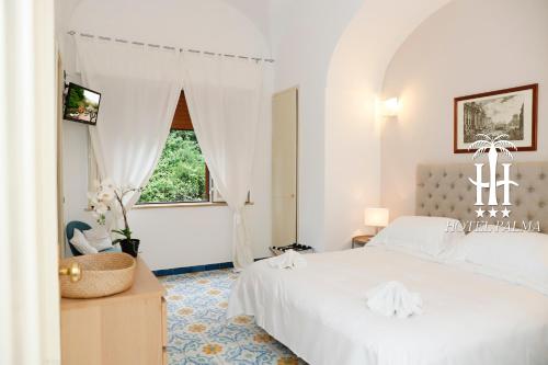 a white bedroom with a bed and a window at Hotel Palma in Castellammare di Stabia