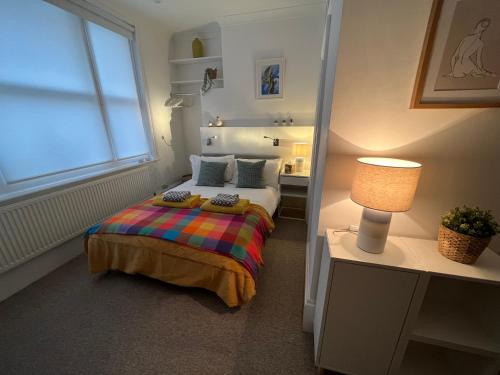 a bedroom with a bed and a lamp and a window at Little Gem in Kemptown Brighton in Brighton & Hove