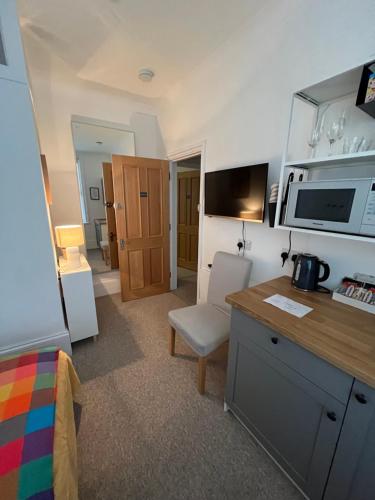a room with a kitchen with a desk and a microwave at Little Gem in Kemptown Brighton in Brighton & Hove