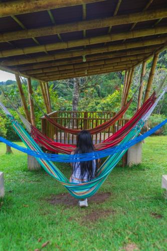 a girl laying in a hammock under a pavilion at La Perla Negra - Black Pearl Eco Hostel in San Rafael