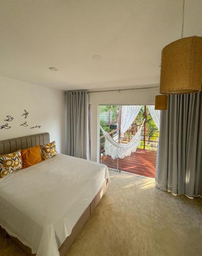 a bedroom with a bed and a sliding glass door at LA RESERVE VILLAS BEIJA-FLOR e IPANEMA in Pipa