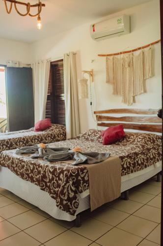 two beds in a hotel room with red pillows at Pousada Paraíso do Vento in Cumbuco