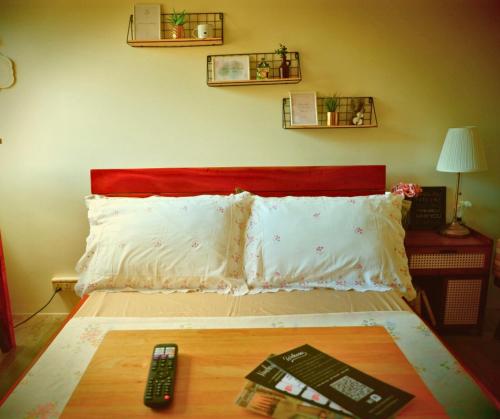 a bed with a red headboard and two remote controls at Stanford Suites, South Forbes - Standard Room with pool in Silang