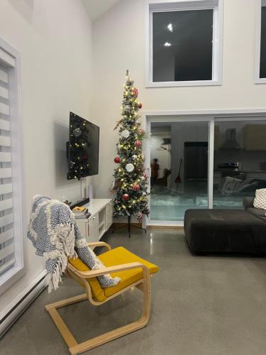 a living room with a christmas tree and a chair at Le Péribonka in LʼAscension