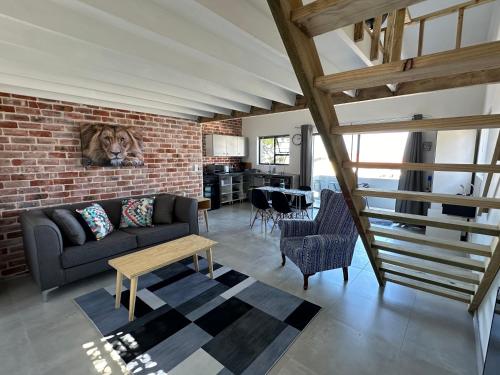 a living room with a couch and a brick wall at Modern apartments downtown in Plettenberg Bay