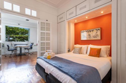 1 dormitorio con 1 cama grande y pared de color naranja en Charme na Urca - Vista arborizada - JLA301 Z5, en Río de Janeiro