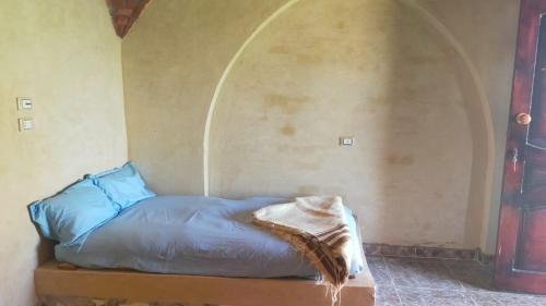 a bed in a room with an arch in the wall at Oum House in Siwa