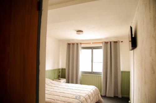a bedroom with a bed and a window at Hostería Las Rosas in Esquel