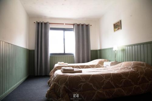 a bedroom with two beds and a window at Hostería Las Rosas in Esquel